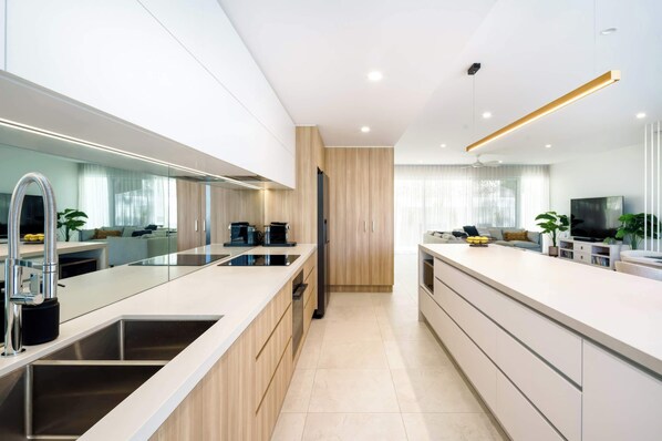 A modern kitchen with a central island, stainless steel appliances, and a dining area with a TV.