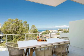 A balcony with a table and chairs, a bottle of wine, and a fruit bowl.