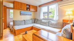 Ein gemütliches Zimmer mit einer Eckcouch, Holzschränken, einem Gemälde und einem Fenster mit Vorhängen.