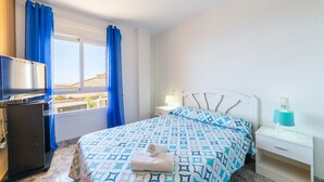Una habitación de hotel con cama, televisión, escritorio y ventana con cortinas.