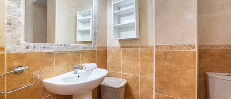 Un baño con lavamanos, espejo y paredes de azulejos.