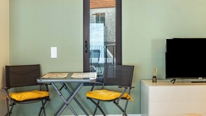 A room with a desk, two chairs, a television, and a door. - Apartment 'Referta Apartamento T1' with Sea View, Private Terrace and Wi-Fi (Prazeres)