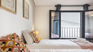 A hotel room with a large bed, a window with a view, and a wall with framed pictures. - Apartment 'Referta Apartamento T1' with Sea View, Private Terrace and Wi-Fi (Prazeres)