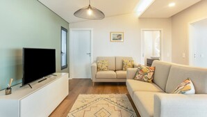 A living room with a flat-screen TV, a sofa, a patterned rug, and a pendant light. - Holiday Home 'Referta House' with Sea View, Private Garden and Wi-Fi (Prazeres)