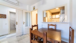 Un comedor con una mesa y sillas de madera, una cocina con refrigerador y estufa, y un baño con inodoro y ducha.