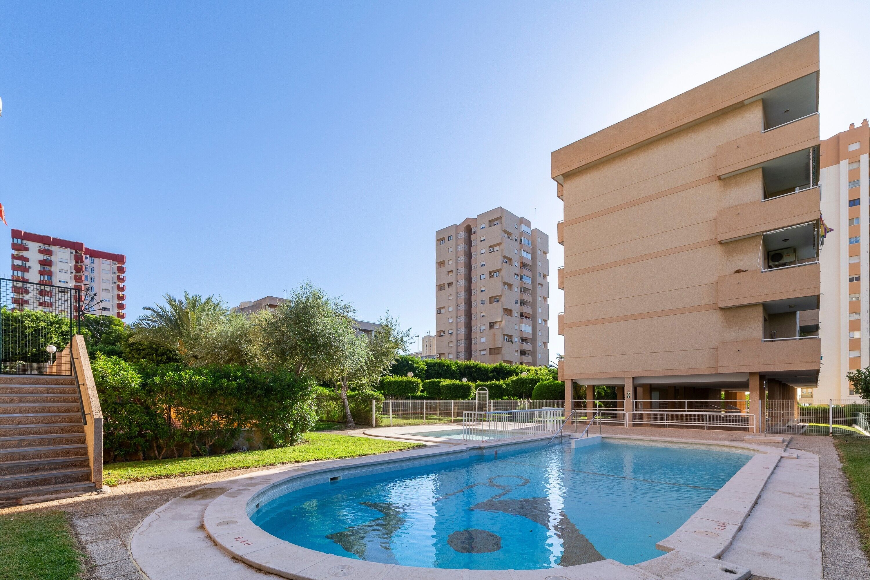 A swimming pool surrounded by greenery and apartment buildings.