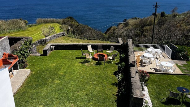 A coastal property with a lawn, outdoor seating, and a view of the sea.