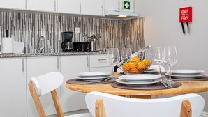 A modern kitchen with white cabinets, a striped backsplash, and a dining area with a wooden table set for two.