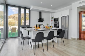 A modern kitchen with a central island, stainless steel appliances, and a view of a hillside. - Holiday Home 'Villa Joya Del Mediterraneo' with Sea Views, Wi-Fi and Air Conditioning (Almuñecar)