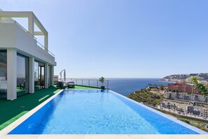Un hôtel moderne doté d’une piscine à débordement sur le toit, offrant une vue imprenable sur la mer.