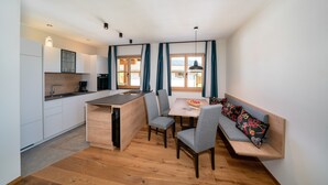 A compact kitchen with a dining area, wooden flooring, and a built-in bench with cushions. - Apartment "Schlosshof Himml" with Mountain View, Private Terrace & Wi-Fi (Fiè allo Sciliar)