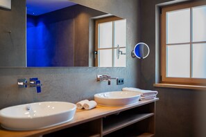 Un baño moderno con dos lavamanos, un espejo grande y una ventana.