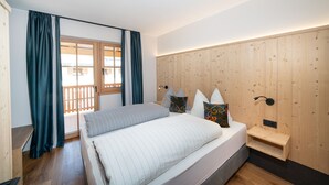 A bedroom with a bed, wooden headboard, curtains, and a view through a window. - Apartment "Schlosshof Himml" with Mountain View, Private Terrace & Wi-Fi (Fiè allo Sciliar)