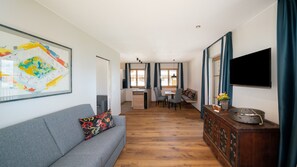 Un salon moderne comprenant un canapé, un coin repas, un téléviseur et un meuble en bois.