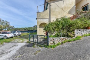 A building with a stone wall, a metal gate, and parked cars.