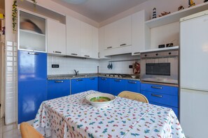 A kitchen with blue and white cabinets, a table with a floral tablecloth, and a bowl on the table.