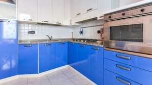 Een keuken met blauwe kastjes, een roestvrijstalen oven en een betegelde achterwand.