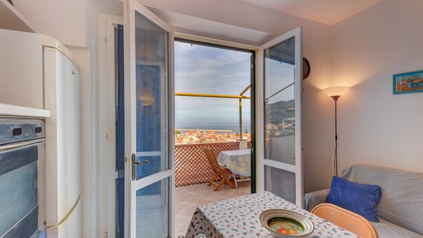 Een open deur die leidt naar een balkon met een tafel, stoelen, een bank en een lamp.