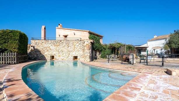 A swimming pool with stone walls and a clear blue water feature. - Country House "Lo Paller" with Mountain View, Shared Pool & Wi-Fi (El Perelló)