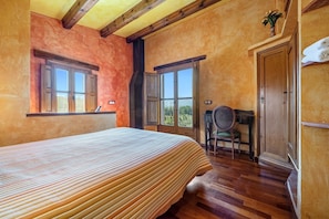 A bedroom with a bed, two windows, a chair, and a door.