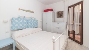 A bedroom with a bed, a wardrobe, a desk, and a window with curtains. - Apartment "Palau Corallo" with Shared Garden & A/C (Palau)
