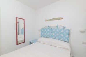 Une chambre à coucher comprenant un lit, un miroir, une table de chevet et un décor mural représentant des poissons.