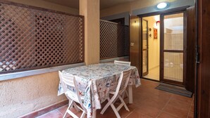 A patio area with a table and chairs, a wooden fence, and a sliding door leading to an interior space. - Apartment "Palau Corallo" with Shared Garden & A/C (Palau)