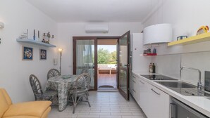 Une cuisine compacte avec un coin repas, un canapé et une vue à travers une porte vitrée.