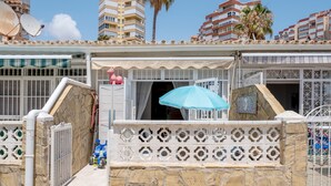A gated entrance with a stone wall, a blue umbrella, and a pink pig statue. - Holiday Home "Beachfront Bungalow" with Sea View, Private Terrace & Wi-Fi (Torrox Costa)