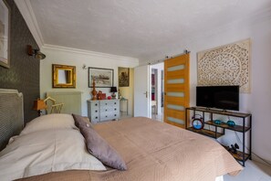 Un dormitorio con cama, cómoda, televisor y objetos decorativos.