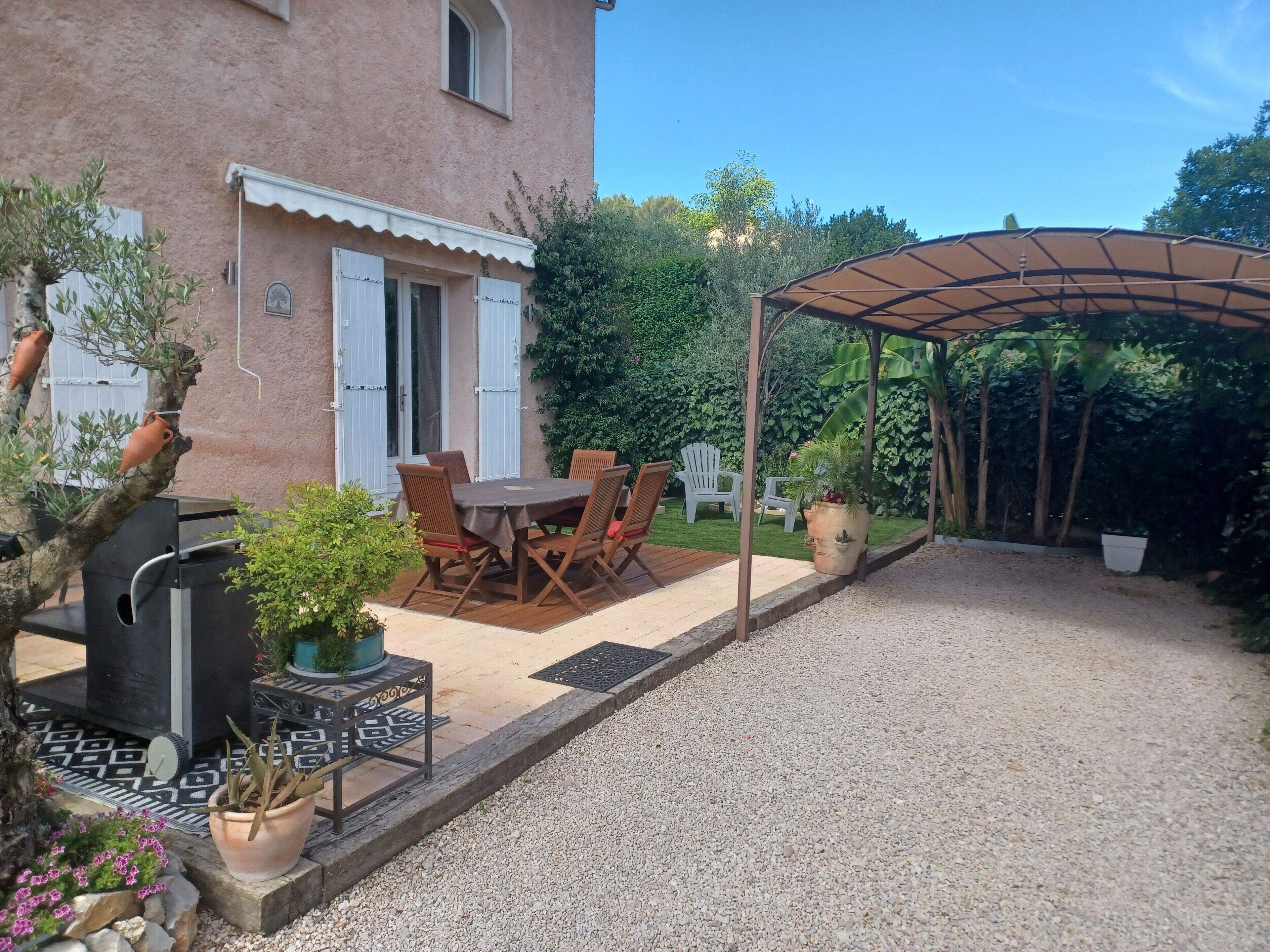 A patio with a table and chairs, a grill, potted plants, and a covered seating area.
