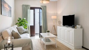 Ein Wohnzimmer mit einer Couch, einem Couchtisch, einem Fernseher, einer Lampe und einer Pflanze.