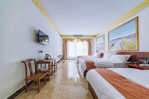 Ein Hotelzimmer mit zwei Betten, einem Schreibtisch mit Stuhl, einem Fernseher und einem großen Fenster mit Vorhängen.