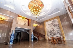 A spacious lobby with a grand chandelier, a large mural, and a staircase leading to upper floors. - Xingchen Haitian Resort (Taishan)
