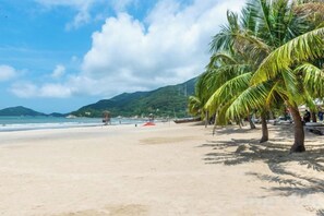 A beach with palm trees, a clear sky, and a calm sea. - Xingchen Haitian Resort (Taishan)