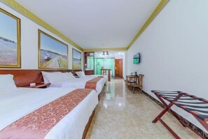 Ein Hotelzimmer mit zwei Betten, einem Schreibtisch, einem Stuhl und einem Fernseher an der Wand.