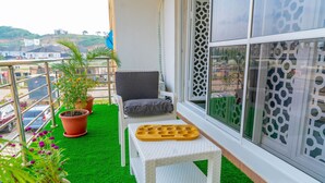 A balcony with a chair, a small table, and potted plants. - Integral Consults Apartment (Abuja)