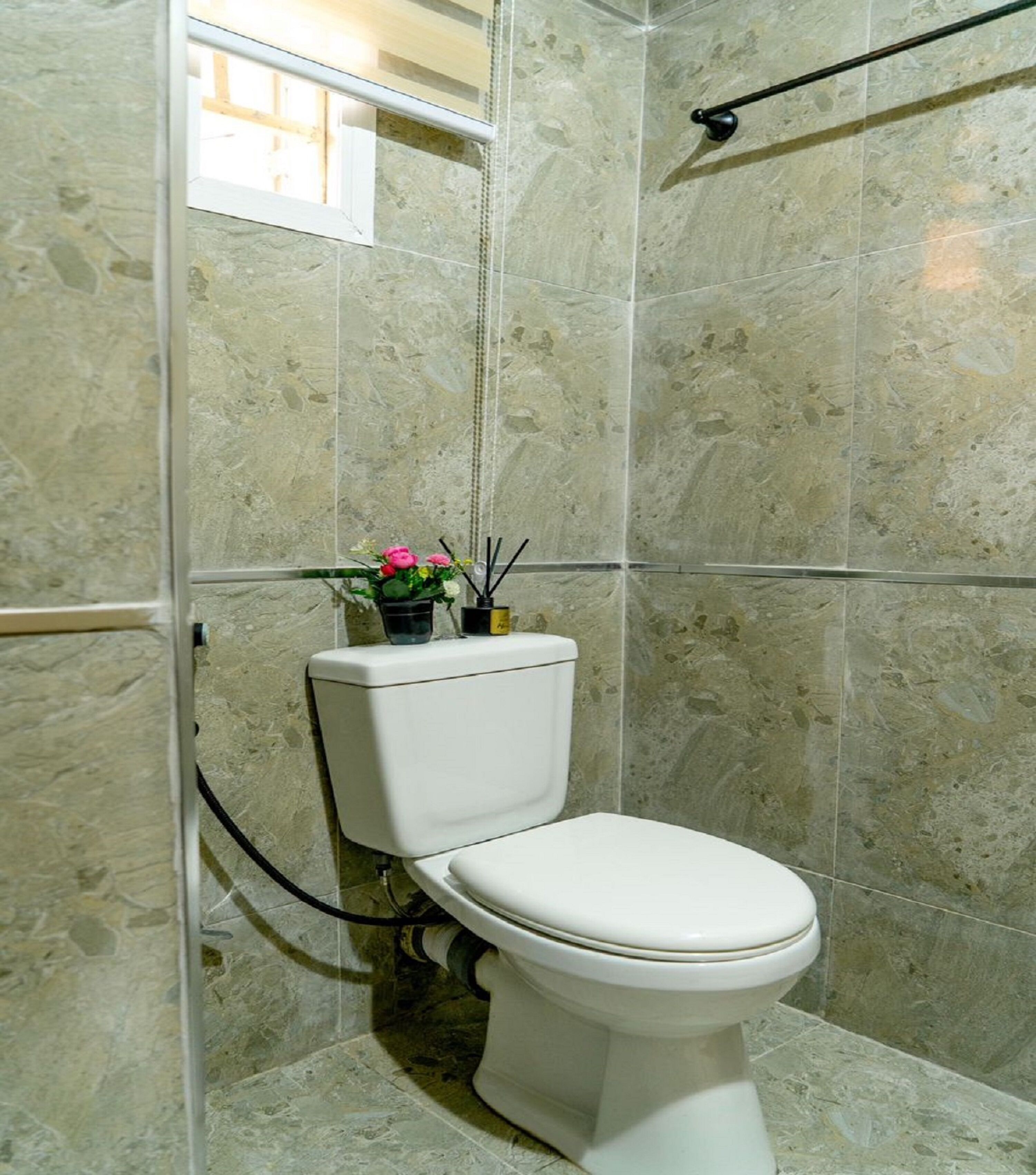 A bathroom with a toilet, a shower area, and a window.