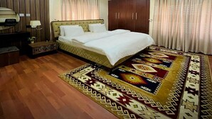 A bedroom with a bed, wooden wardrobe, and curtains. - Integral Consults Apartment (Abuja)