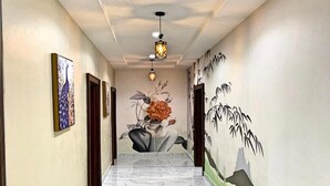 A hallway with a marble floor, a mural on the right wall, and a ceiling light fixture. - Integral Consults Apartment (Abuja)