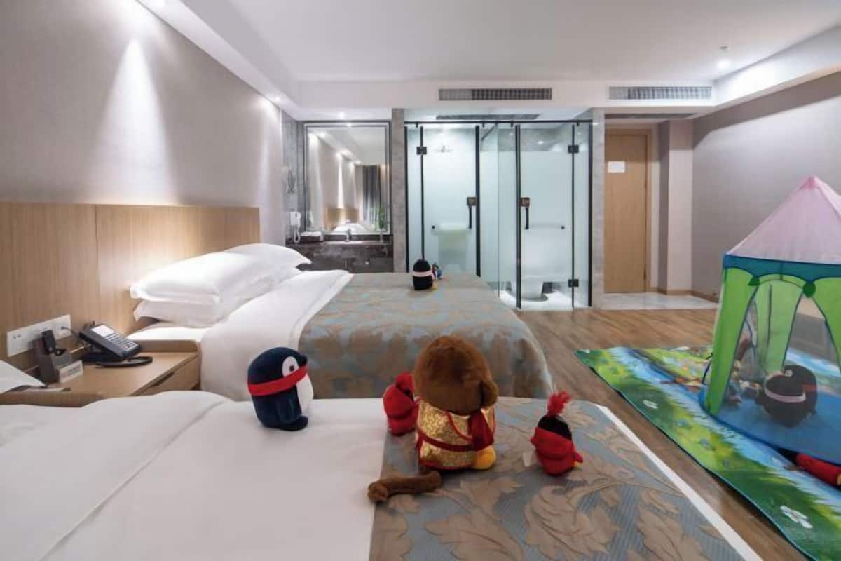 Ein Hotelzimmer mit einem Bett, einem Stofftier, einem Zelt und einem Duschbereich.