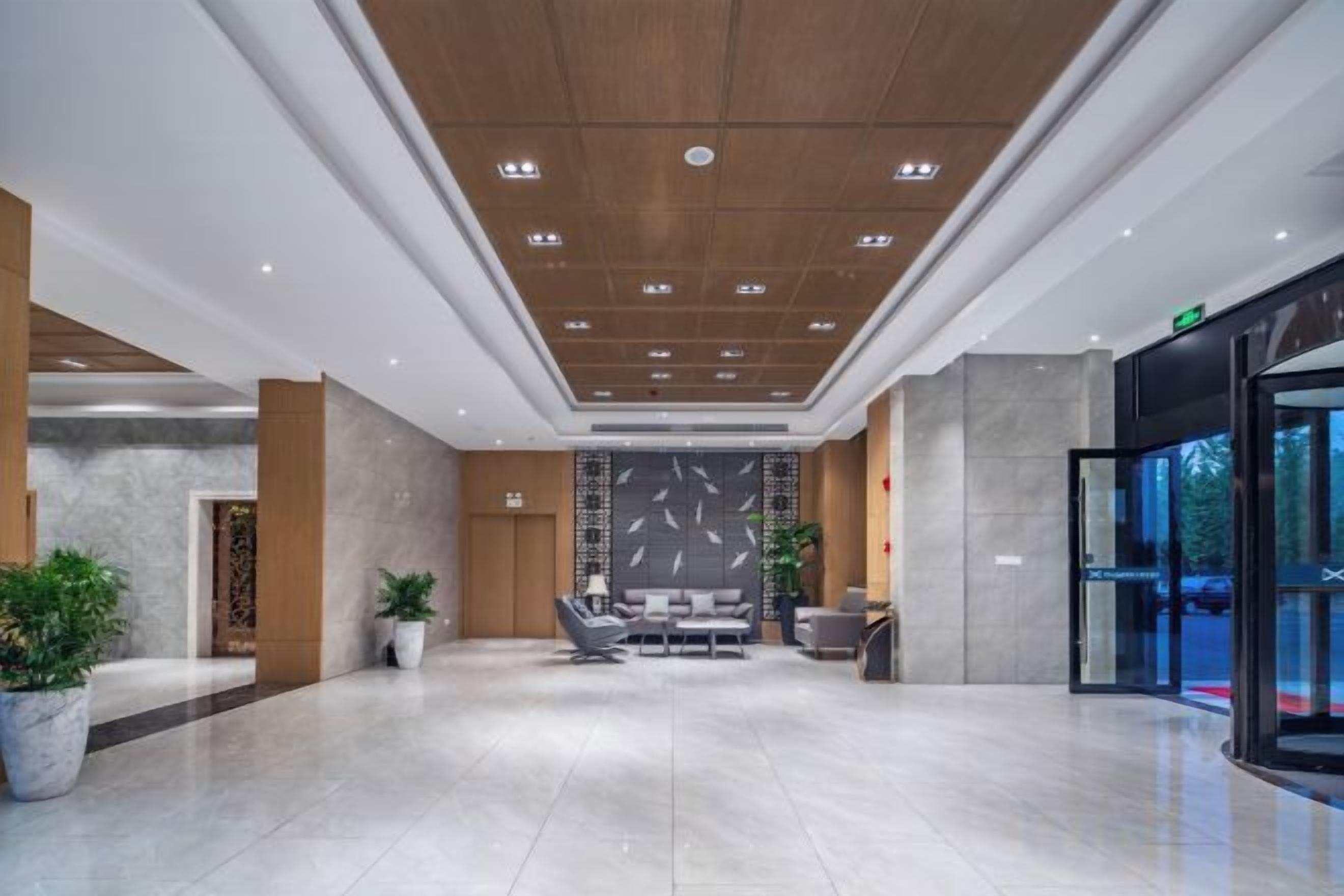 Un hall espacioso con techo alto, zona de estar y entrada por puerta de cristal.
