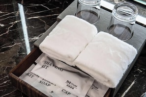 A tray with two white towels and two empty glasses on a marble countertop.
