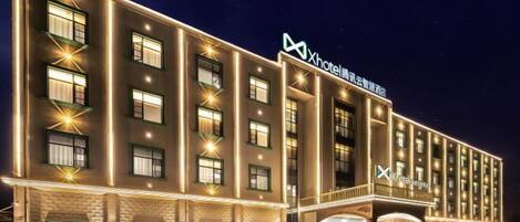 A multi-story hotel with a prominent 'Xhotel' sign, featuring a modern design with evenly spaced windows and a brick facade.