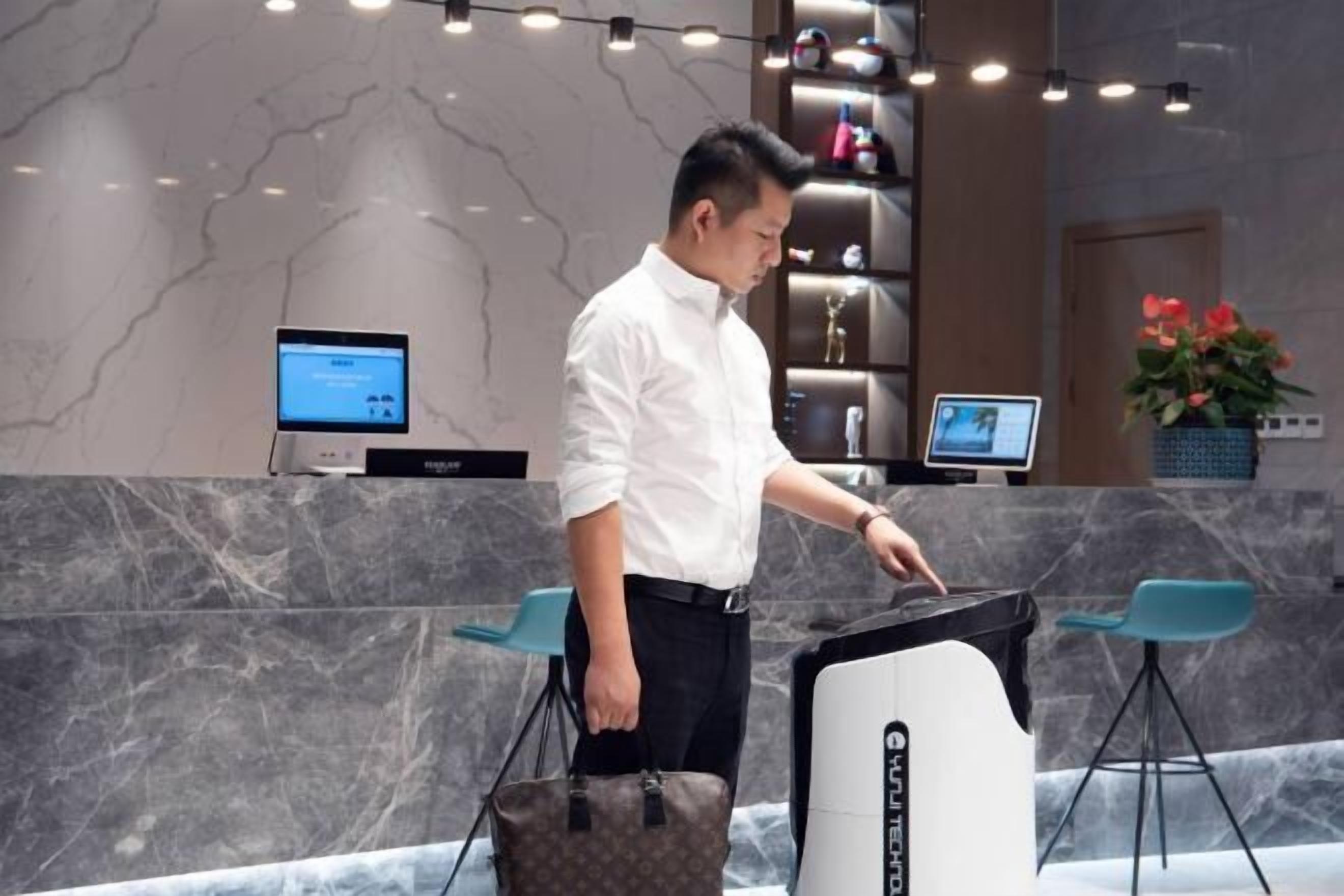 Un hombre en la recepción con un monitor de computadora, un escritorio y una silla.
