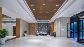 Een ruime lobby met een modern ontwerp, met een zithoek met banken en een bijzettafeltje, een receptiebalie en een glazen entree.