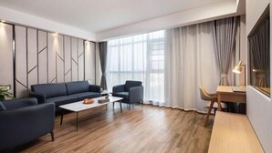 Een moderne woonkamer met een bank, fauteuils, een salontafel en een bureau.