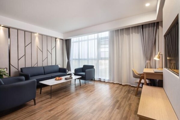 A modern living room with a sofa, armchairs, a coffee table, and a desk.