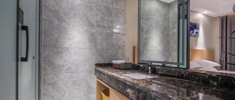 A modern bathroom with a marble countertop, a large mirror, and a towel rack.