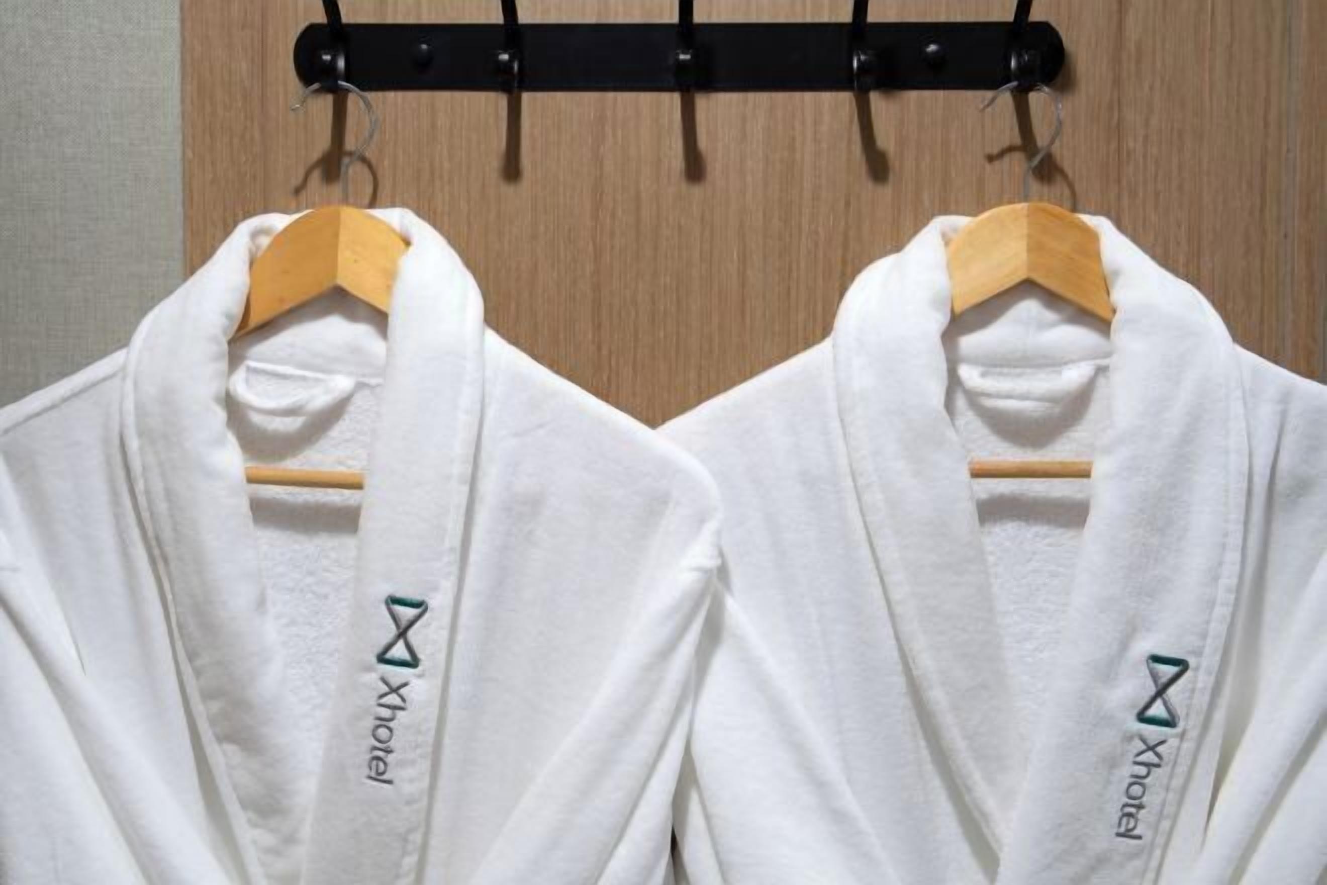 Two white robes hanging on a wooden rack.